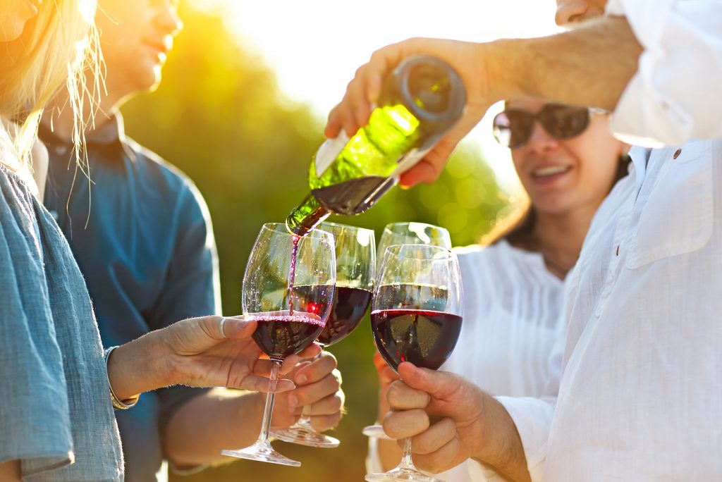 People At Wine Outdoor Party. Wine Festival. Man Pouring Red Wine